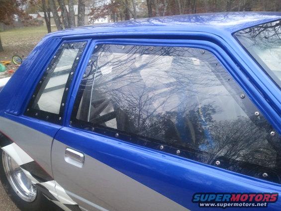 Blue and silver drag car with checkerboard pattern, bolted windows, and roll cage visible inside