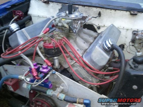 Engine bay showing V8 engine, carburetor, distributor, and fuel lines