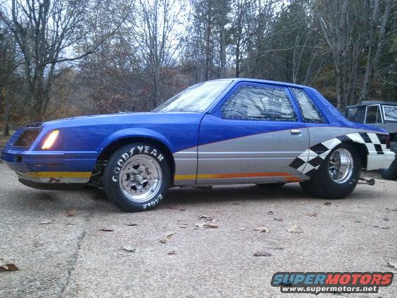 Blue and silver drag car with Goodyear Eagle tires and checkered flag graphics on rear fender