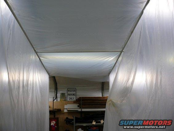 Interior of a temporary structure with plastic sheeting and a 'VISITOR PARKING ONLY' sign