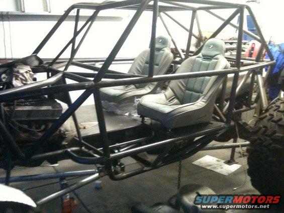 Buggy interior with two bucket seats and roll cage structure. Engine visible in front
