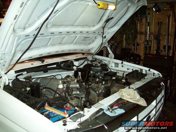 Pickup truck engine bay with hood open. Tools are on the fender