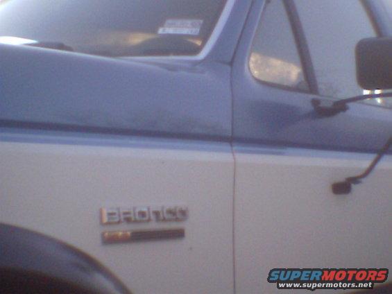 1979 Ford Bronco emblem on side of two-tone vehicle. Supermotors.net logo visible