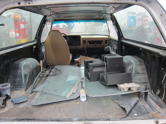 Interior of a 1987 Dodge 1500 pickup truck bed with disassembled parts and seats