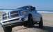 2005 Dodge 1500 - A silver Dodge Ram pickup truck is parked on a beach with the ocean in the background.