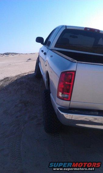 Silver pickup truck on a sandy dune under a clear blue sky