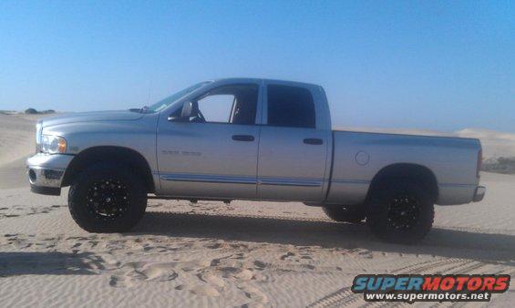 Silver pickup truck with black rims parked on sand dunes