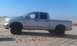 2005 Dodge 1500 - Silver pickup truck with black rims parked on sand dunes under a clear blue sky.