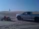 2005 Dodge 1500 - A silver pickup truck and two red ATVs are parked on sand dunes under a clear blue sky.