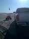 2005 Dodge 1500 - A silver 2005 Dodge 1500 pickup truck is parked on sand dunes, with a red ATV in the background under a clear blue sky.