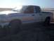 2005 Dodge 1500 - A silver Dodge Ram pickup truck is parked on a sandy beach with the ocean in the background.