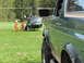 1990 Ford Bronco - A green Ford Bronco is parked in a grassy field next to a helicopter with two people in orange suits.