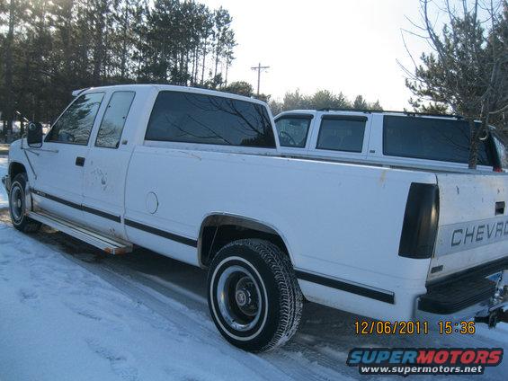 White Chevrolet pickup truck parked in snow, another white vehicle behind it
