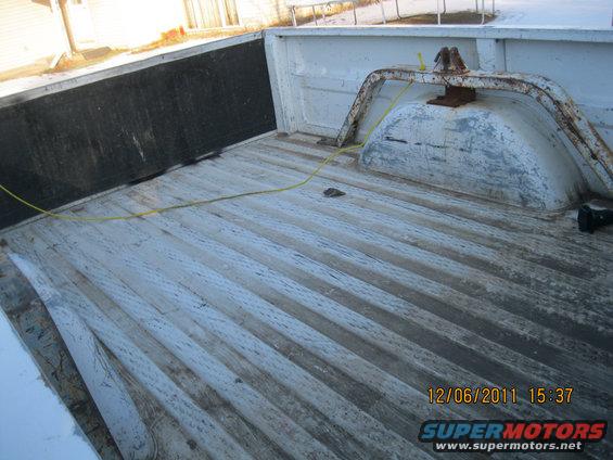 Truck bed with ribbed flooring, a gooseneck hitch, and a yellow cord