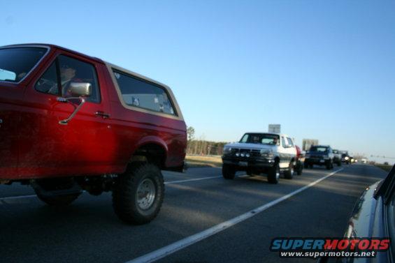 Red 1982 Ford Bronco, 3q-front view, driving on highway