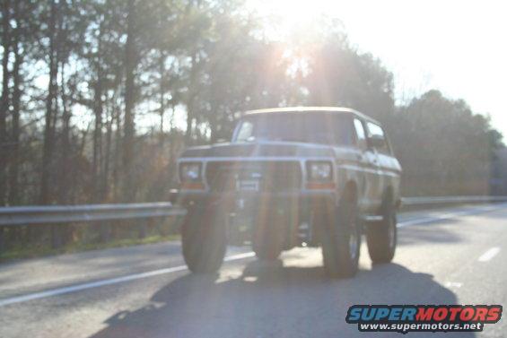 Ford Bronco driving on a road with trees in the background