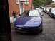 1993 Ford Probe - A blue 1993 Ford Probe is parked in front of a brick building with other vehicles lined up behind it.