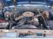 1985 Ford Bronco - The engine compartment of a blue vehicle, revealing its V8 engine and associated components.