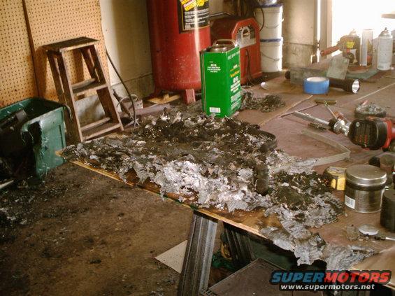 Fire debris covers a workbench in a garage with tools and an air compressor visible