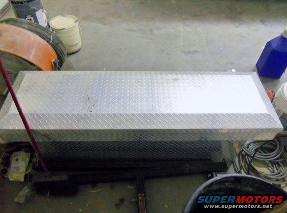 Diamond plate truck tool box on concrete floor with various items