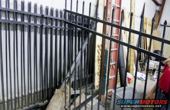 Metal fence panels leaning against a wall with a ladder and other construction items behind them