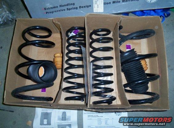 Four new coil springs and two shock absorbers in cardboard boxes