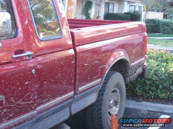 Side view of a red 1995 Ford F-150 covered in mud