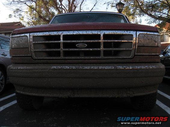 Front view of a muddy 1995 Ford F-150 with a chrome grille and Ford emblem