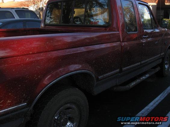 Red 1995 Ford F-150 pickup truck, 3q-front view, covered in mud