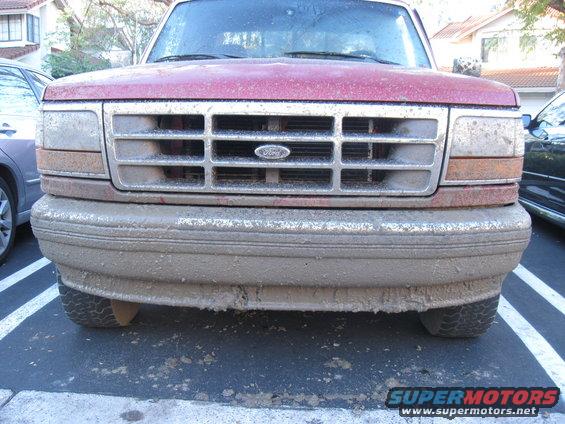 Front of a red 1995 Ford F-150 covered in mud