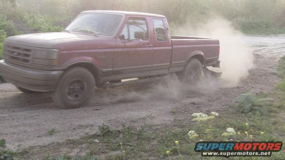 red pickup truck kicking up dust on a dirt road