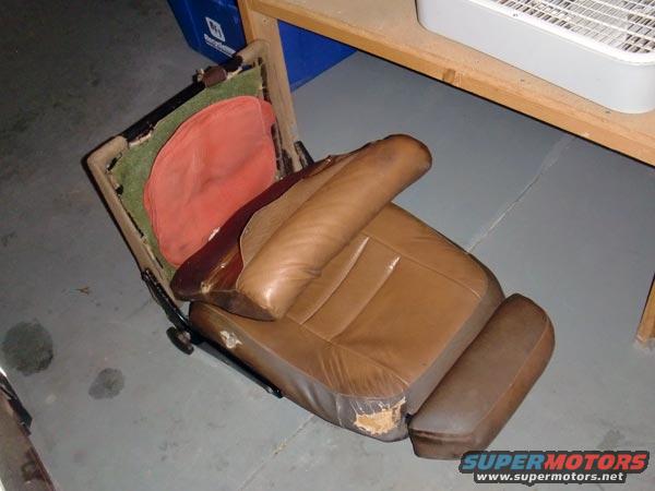 Brown leather car seat with torn upholstery, showing internal padding and frame