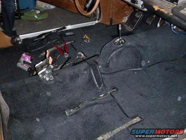 Interior of a car with carpet removed and parts on the floor