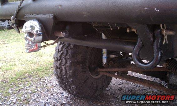 Vehicle rear chassis with large off-road tire, tow hook, and chrome skull taillight