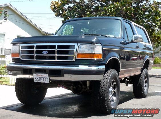 Lifted dark green 1995 Ford Bronco with chrome grille and aftermarket wheels, parked on a driveway