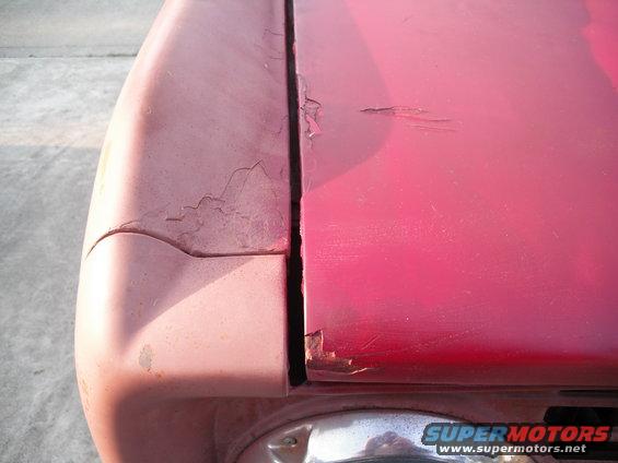 Pink car hood and fender seam with peeling paint and rust