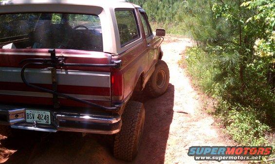 1987 Ford Bronco rear view, red and white, on dirt road