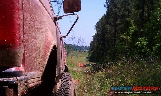 Mud-covered red 1987 Ford Bronco side view, off-road
