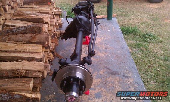 front axle assembly on jack stands next to a pile of firewood