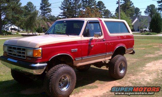1987 Ford Bronco lifted with off-road tires, two-tone red and tan paint