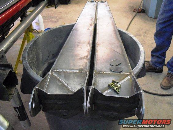 Two fabricated radius arms with hardware, resting in a tub