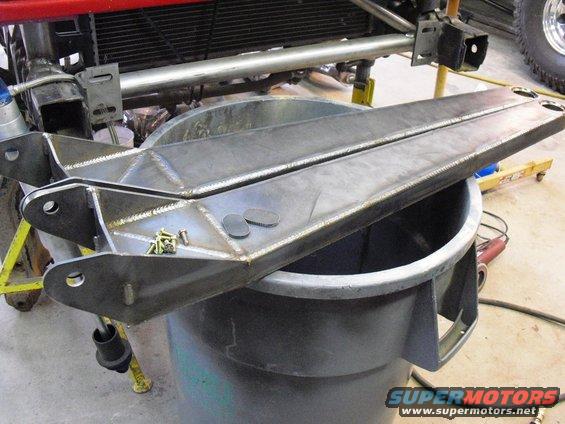 Custom fabricated radius arms with hardware on top, resting on a trash can