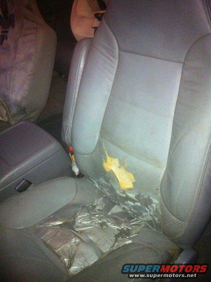 Car interior with torn gray leather seats and yellow stains on the passenger seat