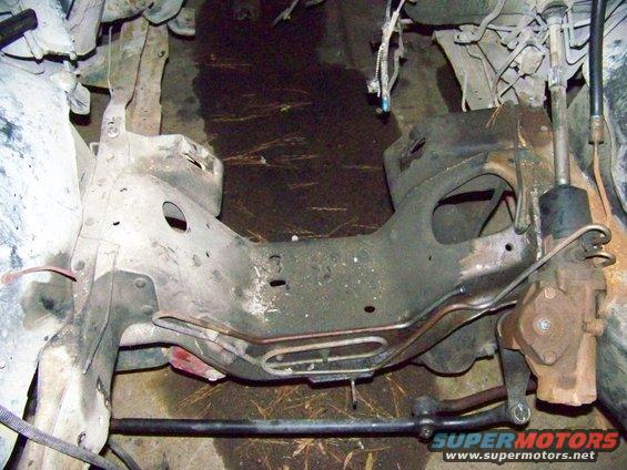 Close-up of vehicle frame, steering box, and tie rods. Supermotors.net logo visible