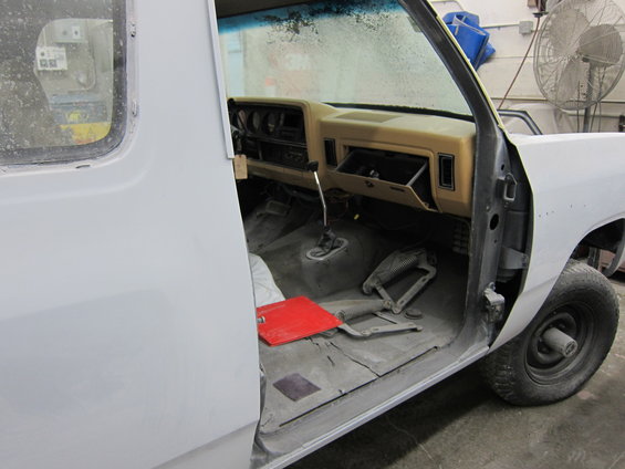 Interior of a 1987 Dodge 1500 pickup truck, showing the dashboard, floor, and open door