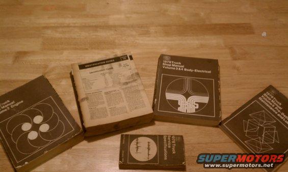 Several shop manuals and an identification guide for 1978 trucks are spread out on a wooden surface