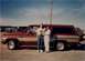 1994 Ford Bronco - A family poses in front of their red and tan SUV, with other vehicles parked behind them.