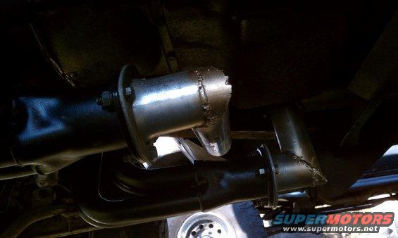 Exhaust pipe with a jagged break, attached to a vehicle's undercarriage