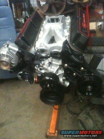Ford V8 engine with aluminum intake manifold and black valve covers. An alternator is visible on the left