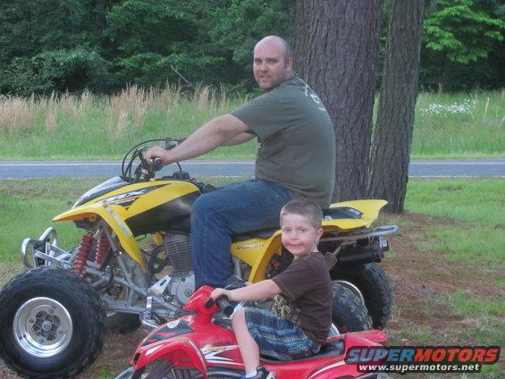 Man and kid on ATVs outside